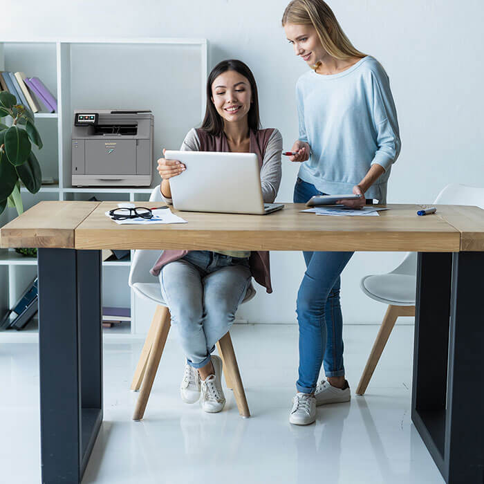 two women looking at laptop on desk in office