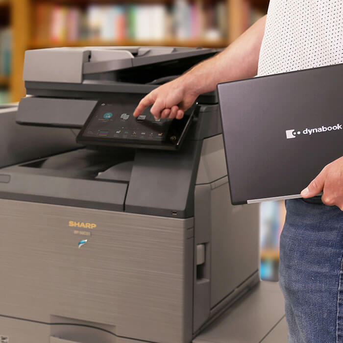 person holding laptop and using office printer