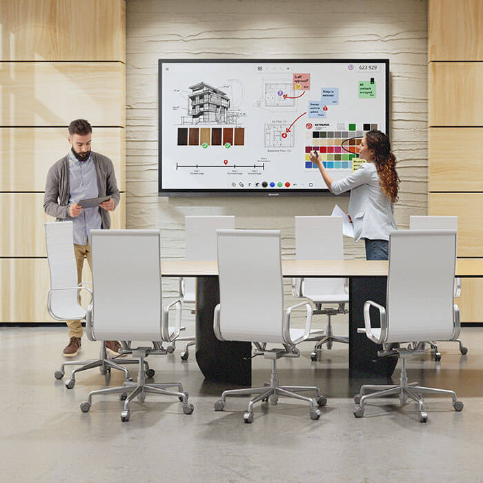 woman using interactive display in meeting room with man