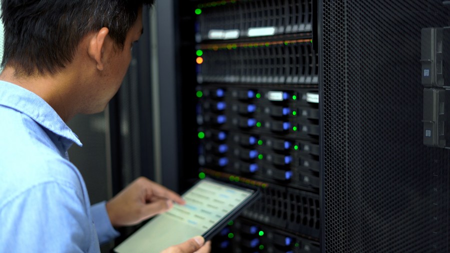 IT technician using a tablet to monitor server rack performance