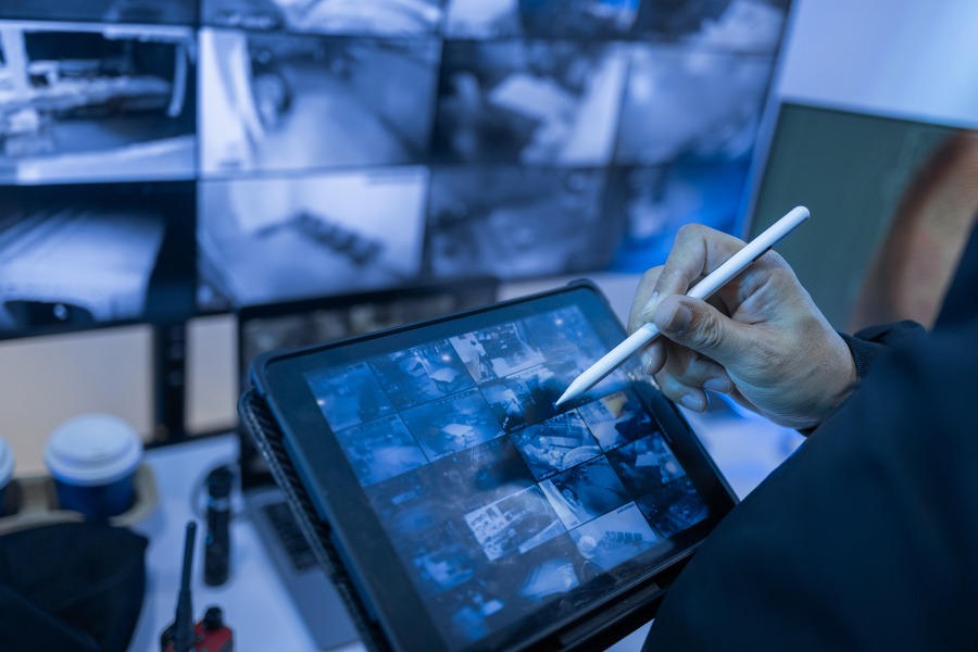 Security professional reviewing surveillance camera feeds on a tablet screen
